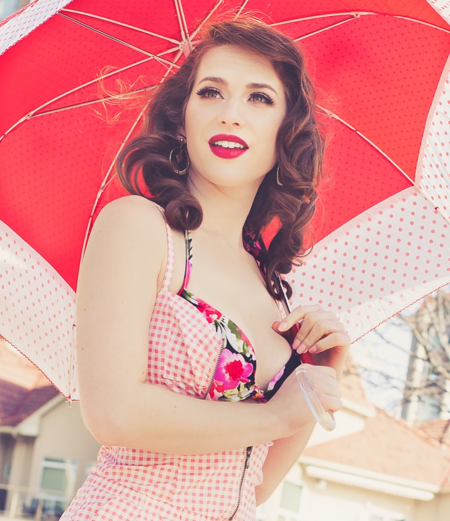 Super glam summer makeup with model wearing bright red lipstick. Model is wearing a floral bikini with a shirt overtop and holding a red umbrella. Makeup by Top Notch Art of Makeup.