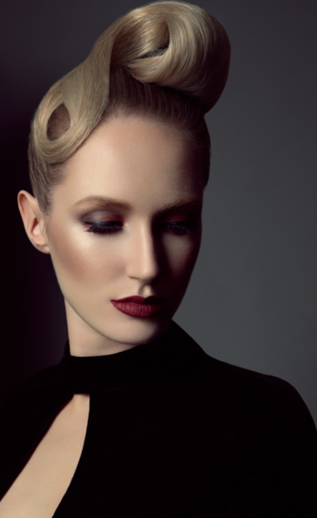 Sophisticated glam makeup with bold red lip on model looking down. Model has blonde hair that is slick and styled up. Makeup by Top Notch Art of Makeup.