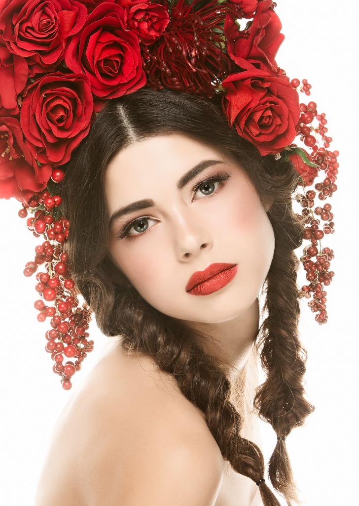 Romantic glam makeup with smokey brown eye and bold red lip on model wearing a red flower crown of red roses. Makeup by Top Notch Art of Makeup