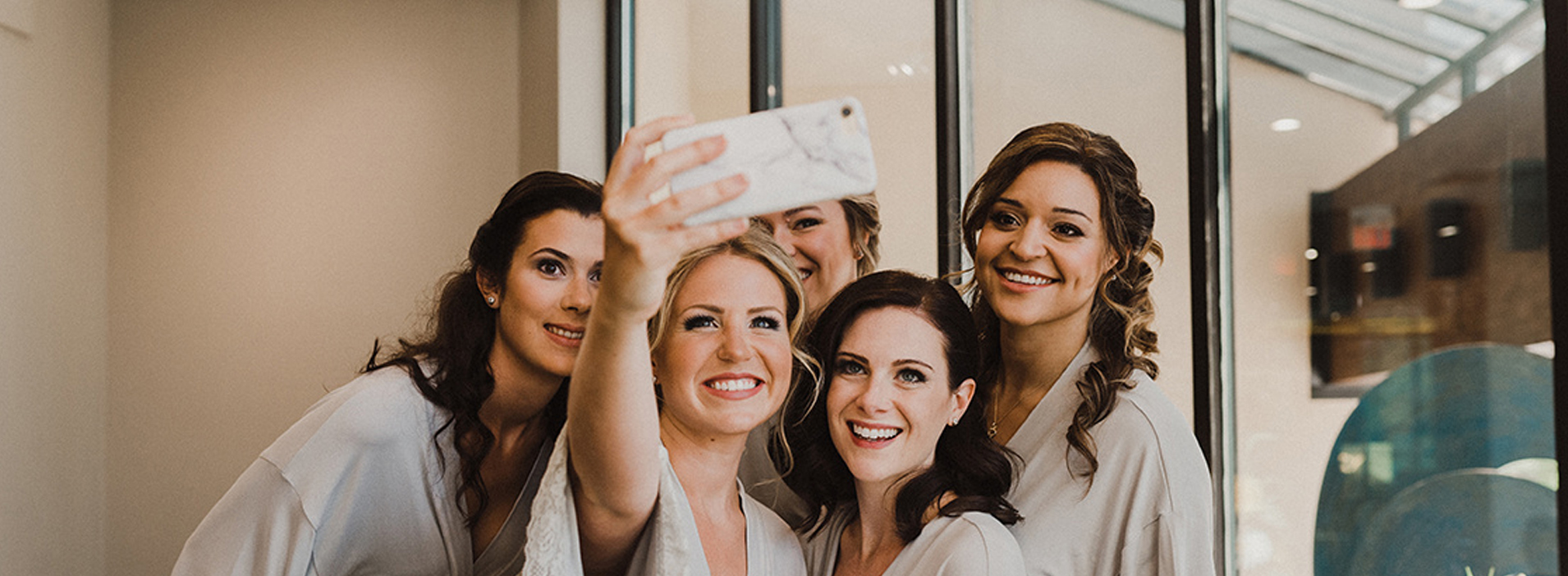 Bridesmaids taking a selfie on wedding day with mobile phone in robes with makeup done by Top Notch Art of Makeup