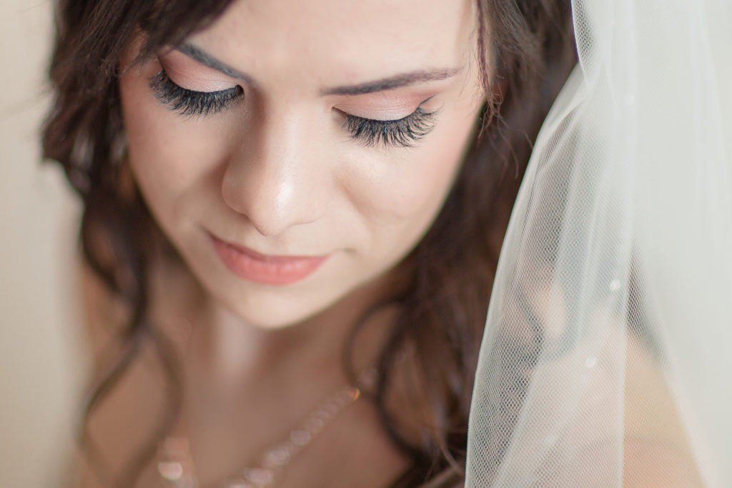 Up close bridal portrait of bride looking down with pink toned eyeshadow and lips. Makeup by Top Notch Art of Makeup.