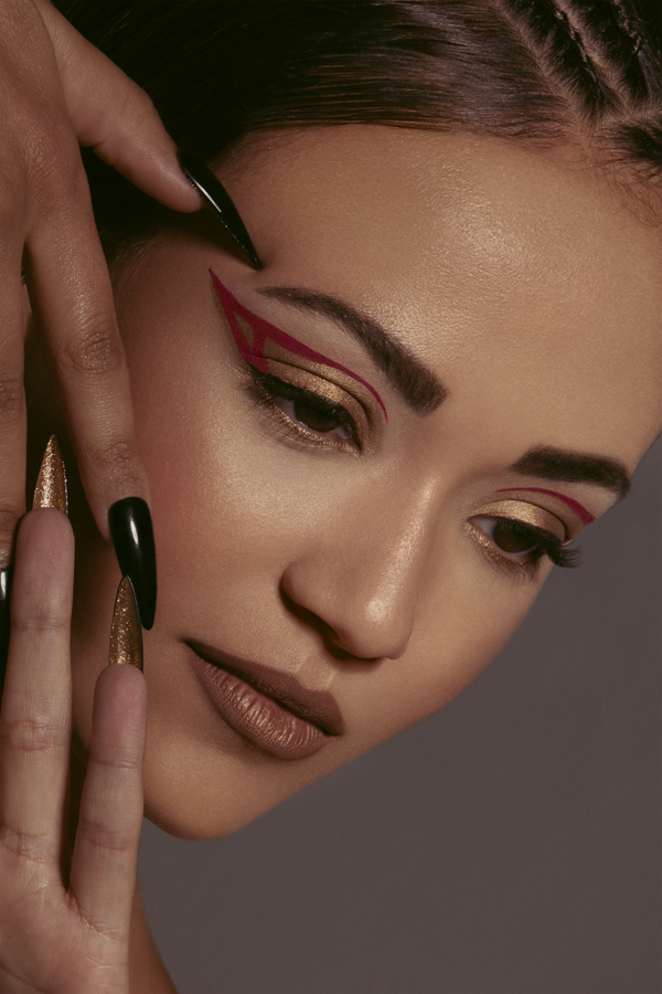 Model touching hands looking dwon with graphic red eye liner.