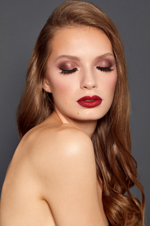 Model looking down with warm chocolate brown eyeshadows and bright red lips